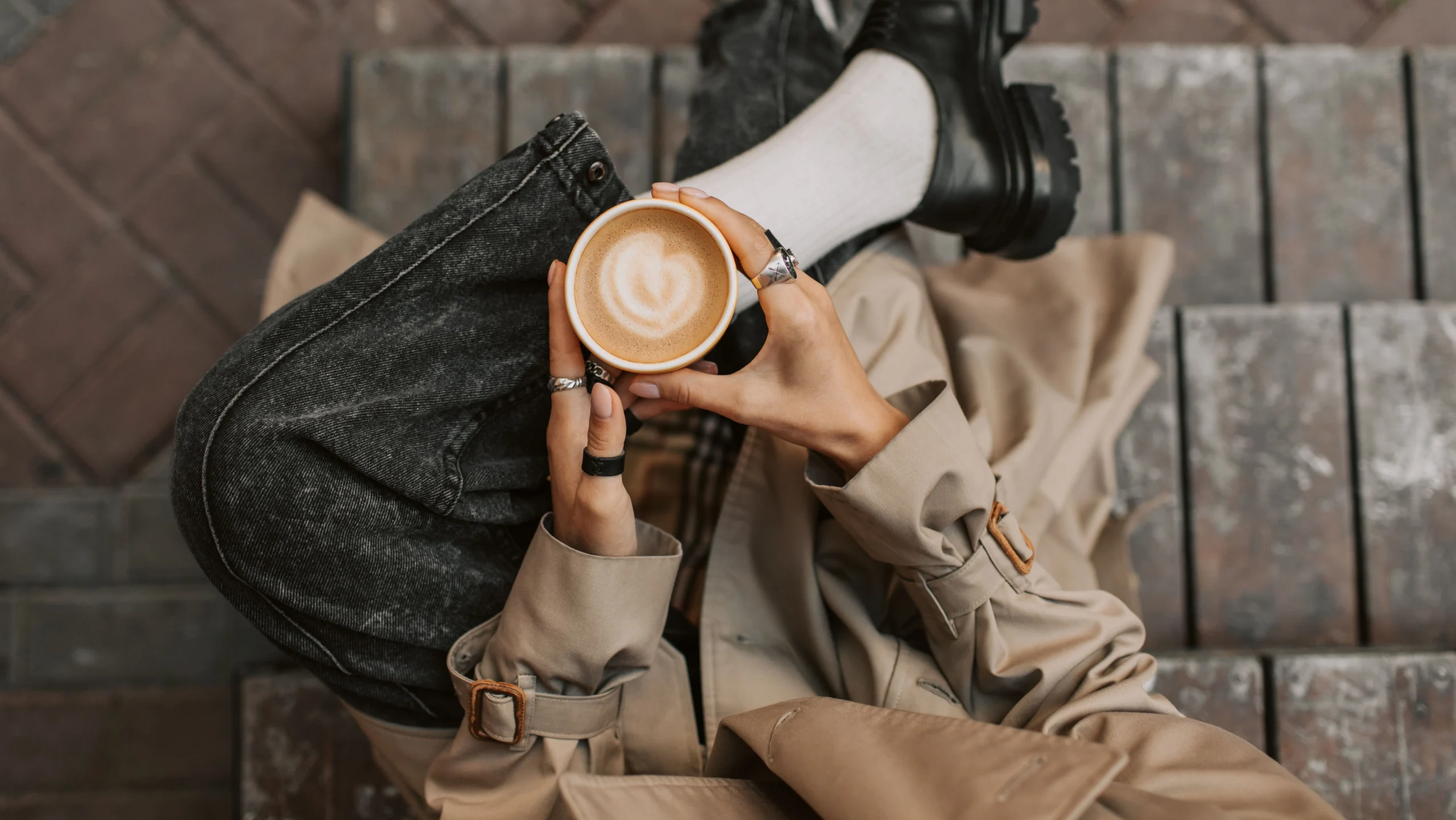Inquadratura dall'alto di un outfit contemporaneo con trench beige d'ispirazione classica e denim scuro