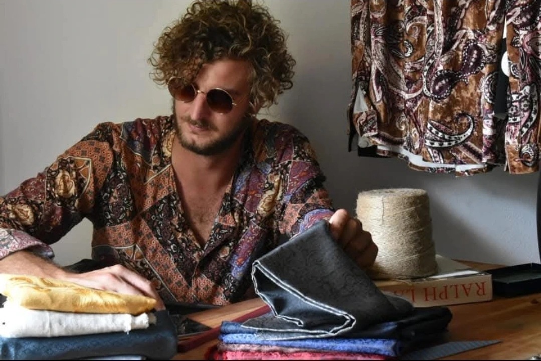 Il designer Michele Roncada al lavoro nel suo laboratorio sartoriale con tessuti vintage per camicie sostenibili
