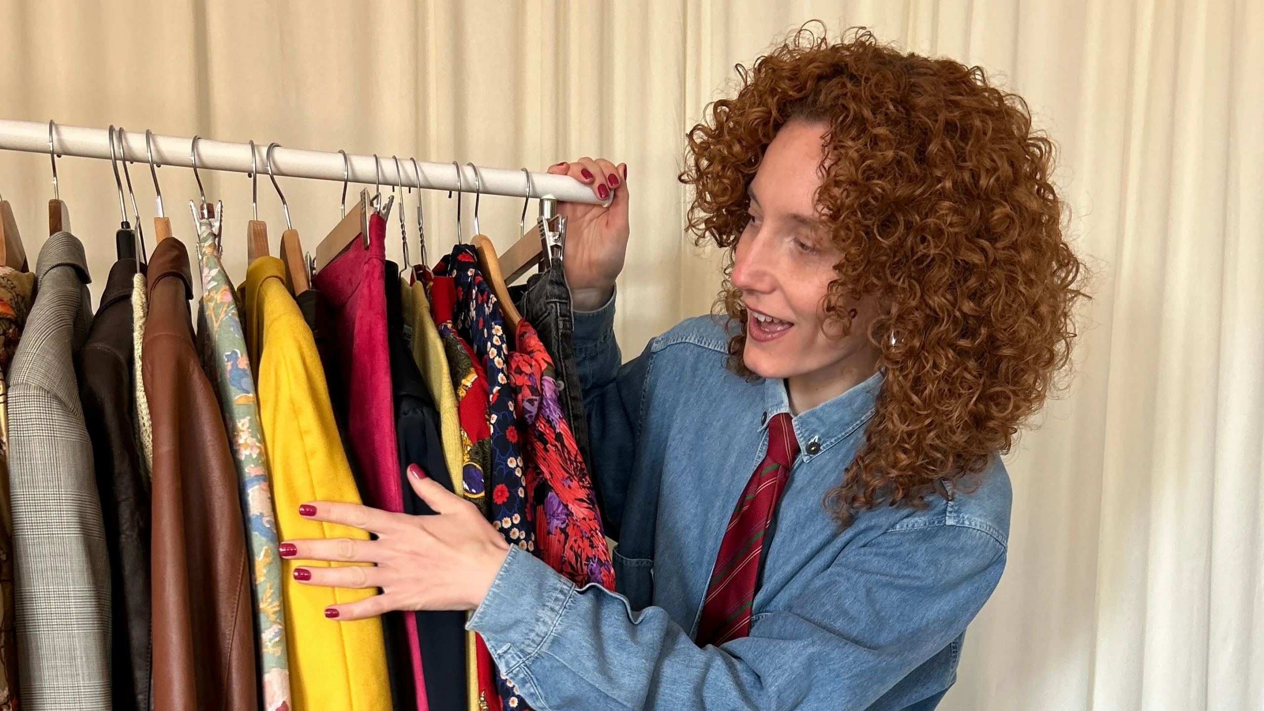 Annalisa Fortunato di Curly Vintage mostra entusiasta una stenderia di abiti second-hand colorati e giacche d'epoca