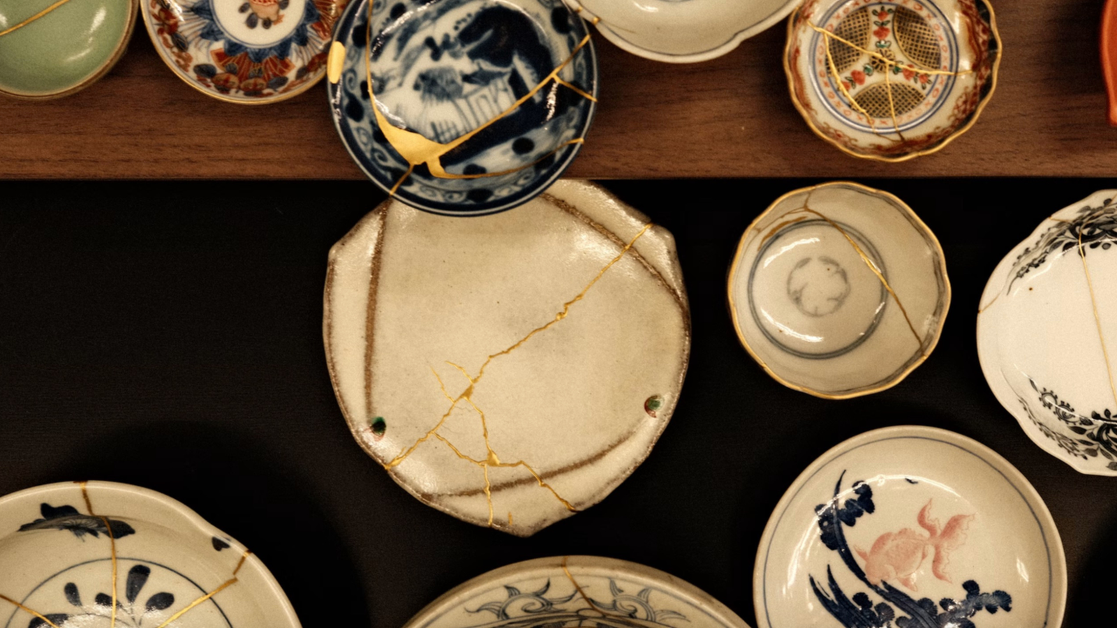 Piatti e ciotole in ceramica artigianale riparati con la tecnica tradizionale giapponese del Kintsugi usando venature d'oro.